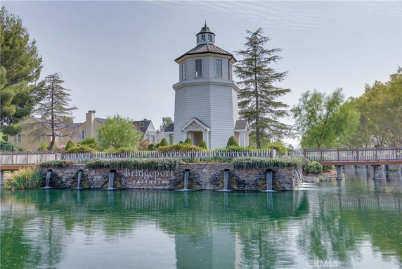 Front view of a lighthouse-style building surrounded by water with a bridge.