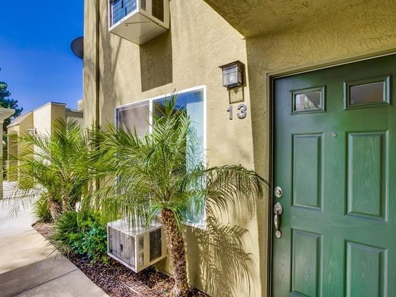 Front view of a house with a green door and air conditioning units.