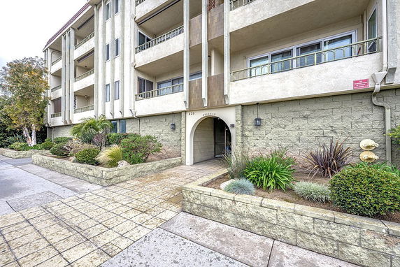 Front view of a multi-story building with balconies and an arched entrance.