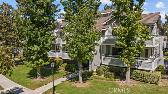 Front view of a multi-story residential building with balconies and trees in front.