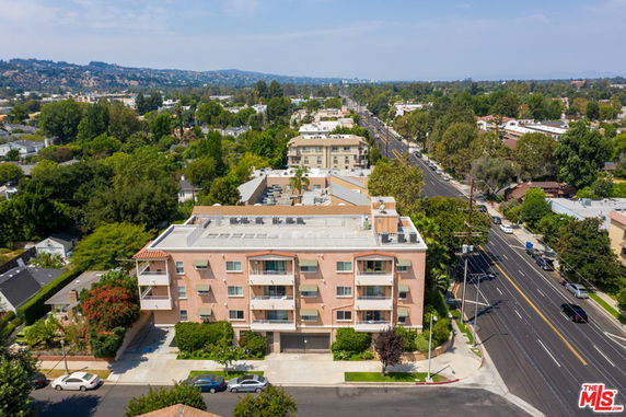 Front view of a multi-story residential building with balconies and a flat roof.