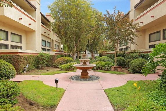 Central courtyard of an apartment complex featuring a fountain and surrounding landscaped greenery.