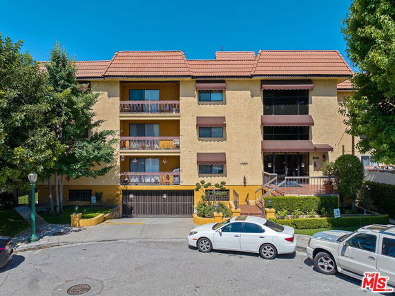 Front view of a multi-story building with a sloped roof and balconies.