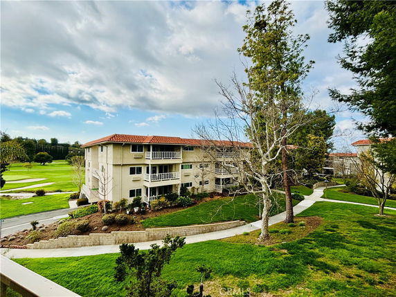 View of an apartment building with balconies surrounded by greenery and trees.