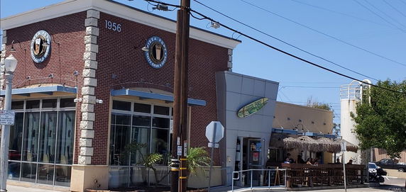 Front view of a building with large windows and a brick facade, featuring a restaurant sign.