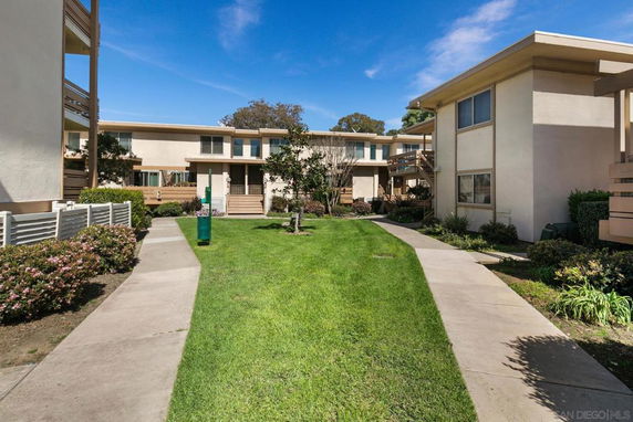 Front view of a two-story apartment complex with a central grassy courtyard.
