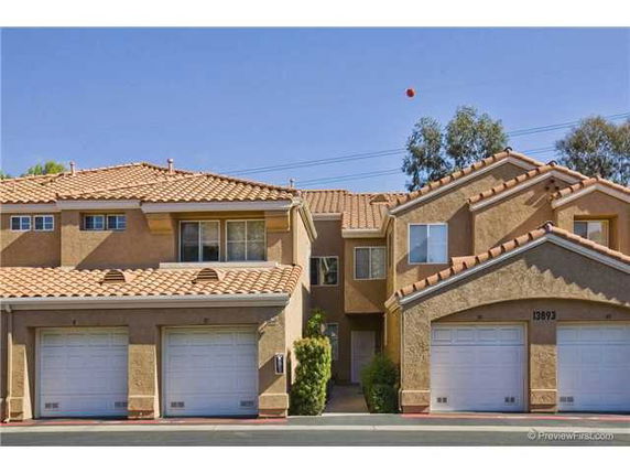 Front view of a multi-story house with a tiled roof and garage doors.