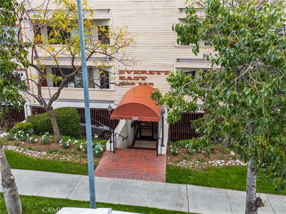 Front view of a building entrance with an orange canopy and brick walkway.