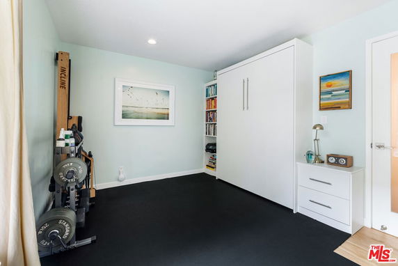 Indoor gym area with exercise equipment and a fold-down bed.