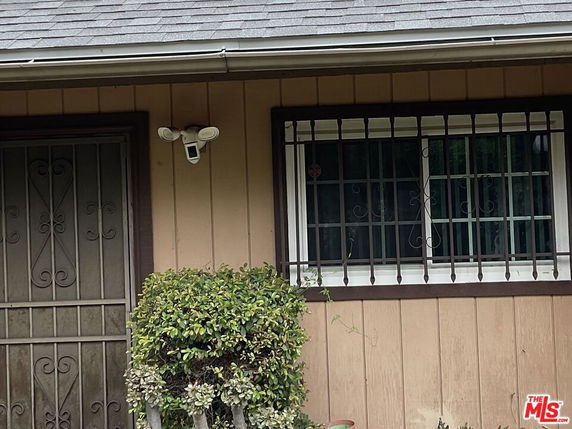 Front view of a house with a security camera and barred window.