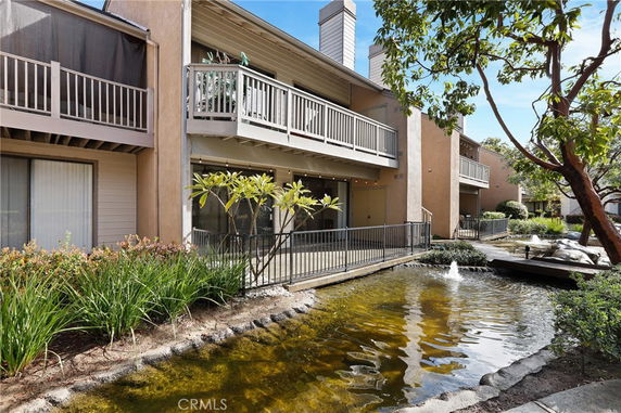 Front view of a two-story building with balconies overlooking a small pond.