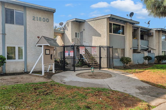 Front view of a multi-story apartment with gated entrance and balconies.