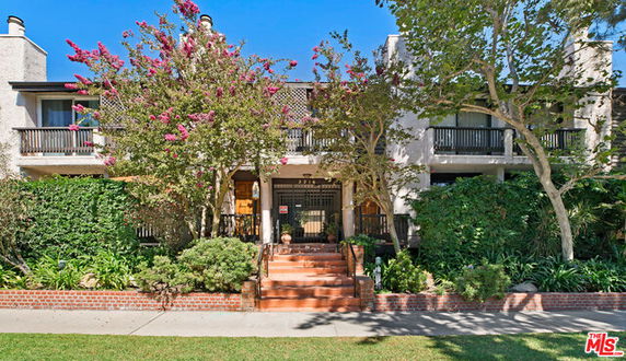 Front view of a multi-story building with balconies and a garden entrance.