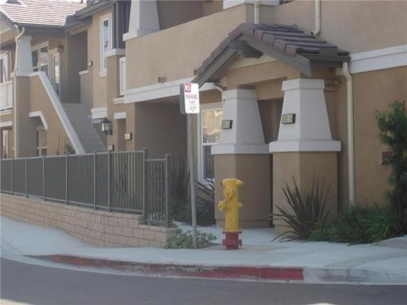 Front view of a multi-story townhouse with a fenced entrance.