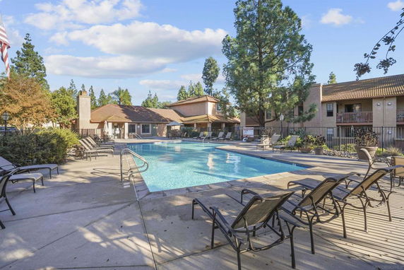 Outdoor swimming pool area with lounge chairs and surrounding buildings.