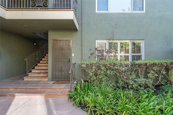 Entrance of a building with stairs and a metal door on the ground floor.