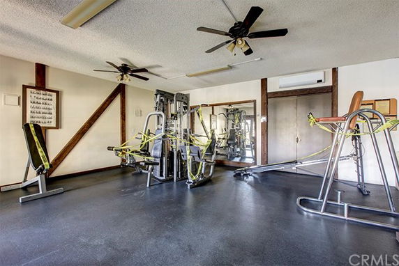 Indoor gym area with various exercise equipment and ceiling fans.