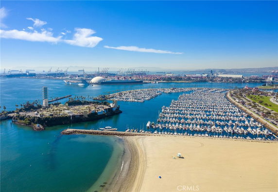 Wide angle view of a harbor with numerous boats and nearby industrial area.