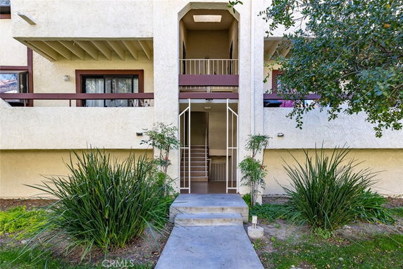 Front view of a two-story building entrance with a small staircase and metal railing.