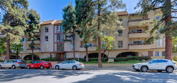Front view of a multi-story apartment building with balconies and arched entryways.