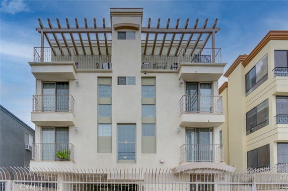Front view of a multi-story building with balconies and a decorative rooftop structure.