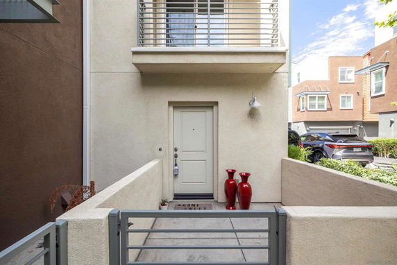 Front view of a modern townhouse with a small entrance area and second-story balcony.