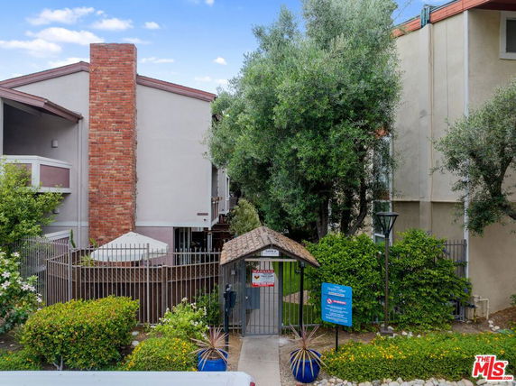 Front view of a multi-story building with a brick chimney and gated entrance.