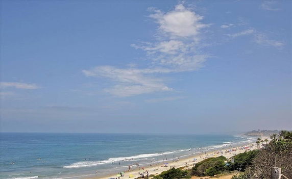 Panoramic view of a beach and the ocean with people along the shore.
