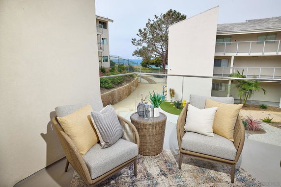 View from a balcony showing multiple residential buildings with a seating area in the foreground.