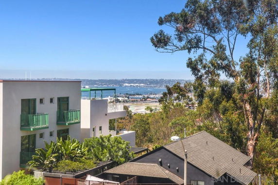 View from a building overlooking other structures and a body of water in the distance.