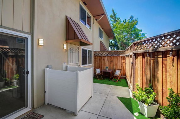 Front view of a two-story house with a small patio area and wooden fence.