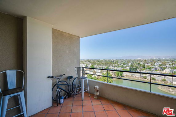 Balcony view with seating and bicycle, overlooking a panoramic view of a city and waterway.