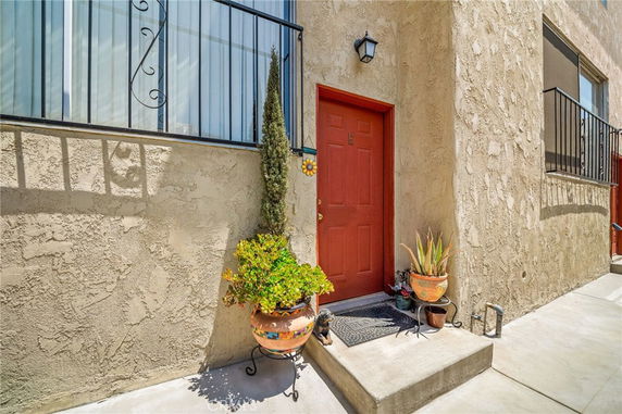 Front view of a building with a red door and decorative plants.