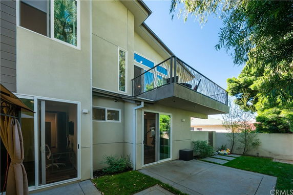 Exterior view of a two-story house with a balcony and large windows.