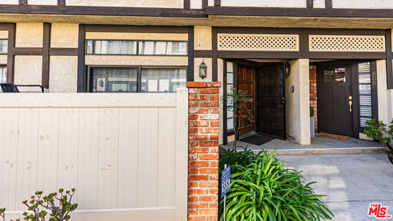 Front view of a house with a combination of brick and beige exterior walls, featuring a prominent doorway and windows.