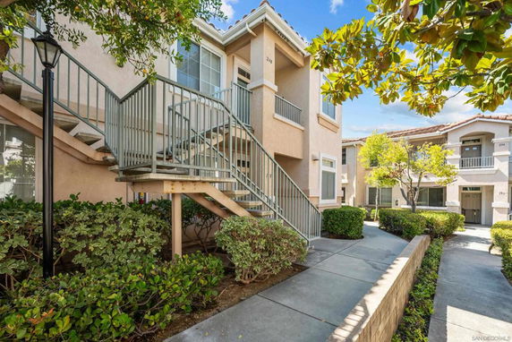Front view of a two-story residential building with external staircase and landscaped walkway.