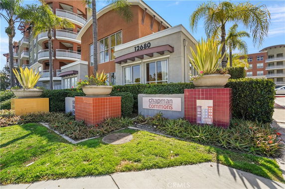 Front view of a multi-story building with balconies and decorative planters in front.