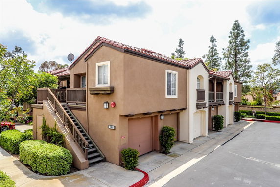Front view of a two-story residential building with a red-tiled roof and exterior staircase.