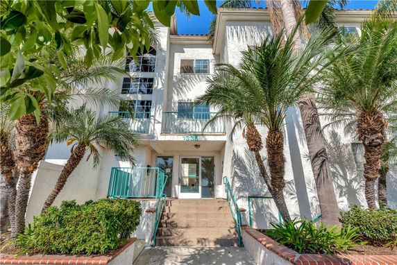 Front view of a multi-story building with palm trees and entrance steps.