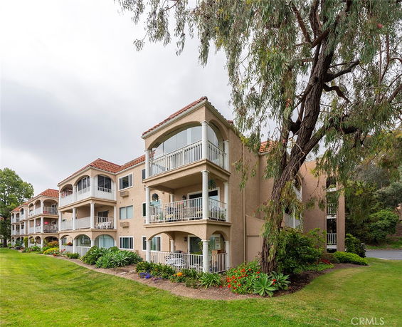 Front view of a multi-story residential building with balconies and a sloped roof.