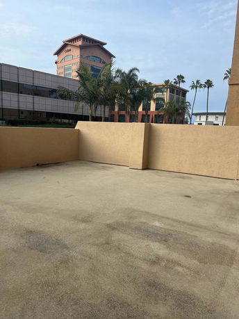 View from a rooftop area showing nearby buildings and palm trees.