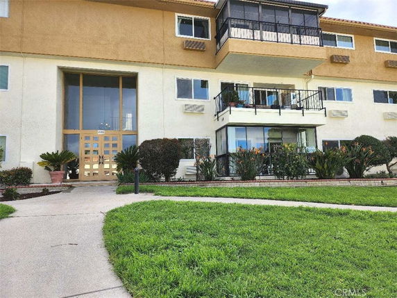 Front view of a multi-story apartment building with a central entrance and several balconies.