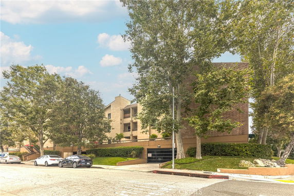 Front view of a multi-story building with a brick facade and trees nearby.
