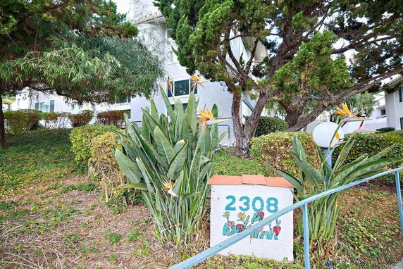 Front view of a building partially obscured by trees with visible house number 2308.