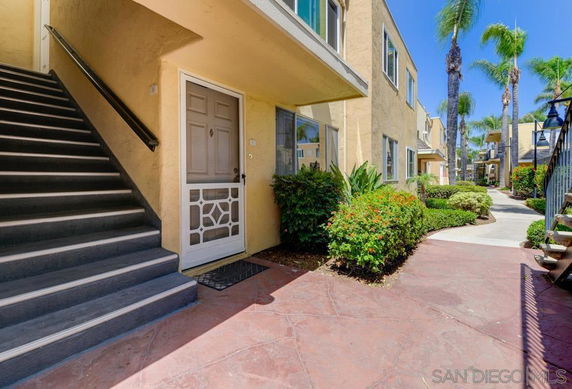 Front view of a multi-story residential building with a staircase and entrance door.