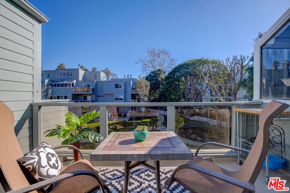 View from a balcony showing residential buildings and a garden area.