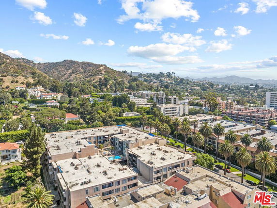 Panoramic view of a hilly landscape with residential buildings and palm trees.