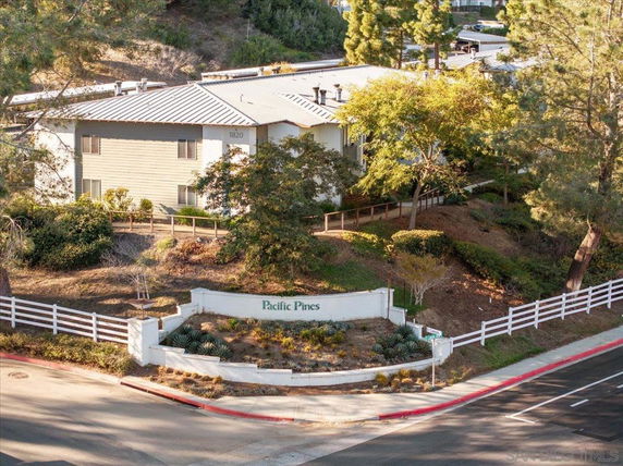 Elevation view of a multi-story building with a sloped roof and surrounded by trees.