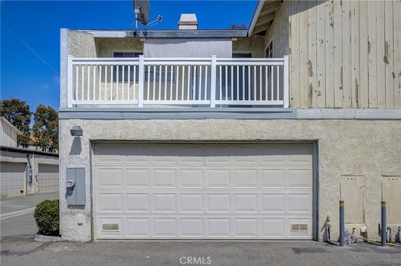 Front view of a two-story house with a garage and a balcony.