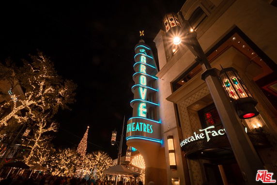 Front view of a theater entrance with illuminated signage and decorative lights at night.